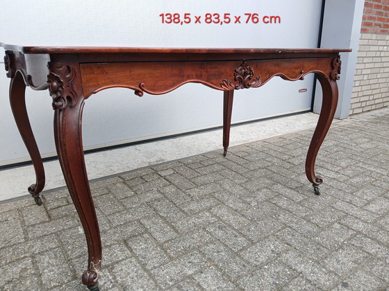 Image 1 of The antique dining table is made of mahogany and has a Louis XV style.