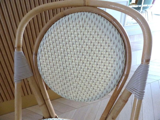 Image 1 of Een paar Parijse bistrostolen van Maison Louis Drucker in licht Manila-rotan.