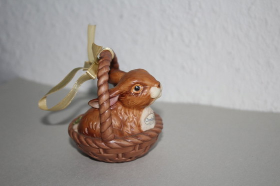 Image 1 of Un conejito adorable en una cesta con una flor amarilla. Goebel Edición Limitada Sorpresa de Pascua 2001