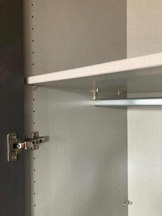 Image 1 of Hoher, dunkelgrauer zweitüriger Kleiderschrank mit vertikalen silbernen Griffen.