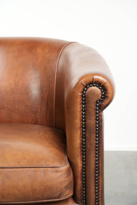 Image 1 of Poltrona club in montone color cognac caldo, rifinita con borchie decorative.