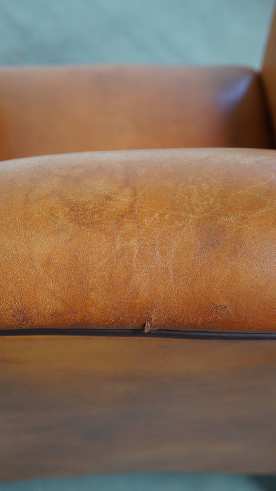 Image 1 of Schapenleren armchair met een afwerking met donkerbruine biezen