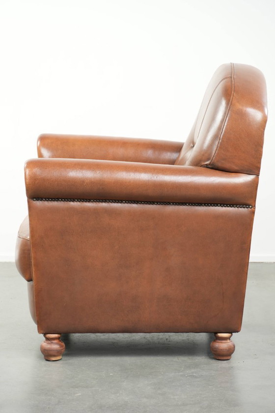 Image 1 of Fauteuil en bon état, en peau de mouton avec une finition raffinée et des clous décoratifs.