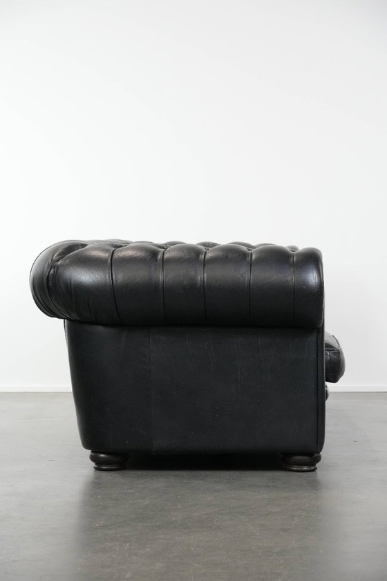 Image 1 of Set consisting of a black Chesterfield sofa, armchair and footstool made of cowhide