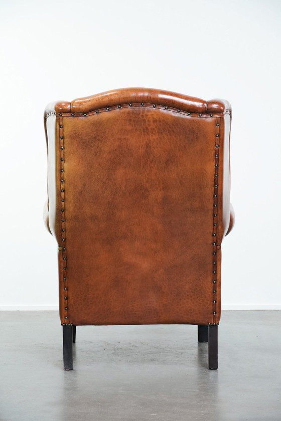 Image 1 of Grote schapenleren oorfauteuil met zwarte biezen en siernagels