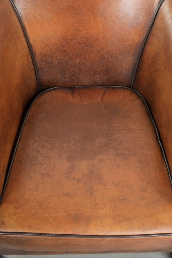 Image 1 of Schapenleren clubfauteuil met een mooie patina en een verfijnde afwerking met zwarte biezen