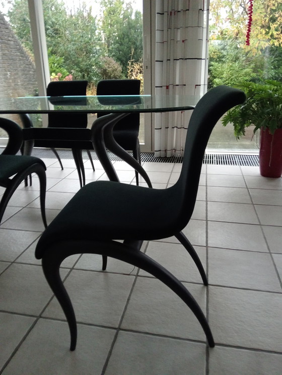 Image 1 of Mesa de comedor ovalada de cristal con 4 sillas negras a juego.