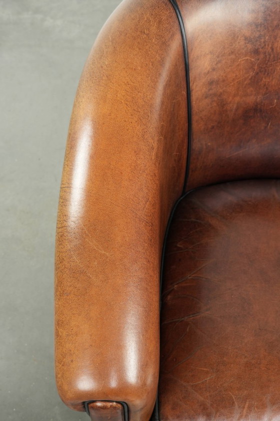 Image 1 of Mooie en karaktervolle schapenleren clubfauteuil met mooie diepe warme kleuren, zwarte biezen en een comfortabele zit