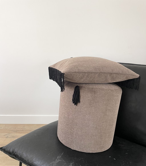 Pouf e cuscino realizzati a mano con dettagli a frange nere.