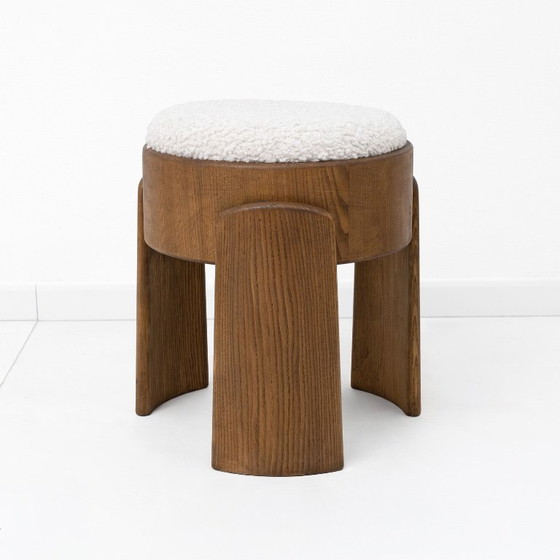 Image 1 of Een paar Art Deco-stijl krukjes van essenhout, bekleed met witte boucléstof.