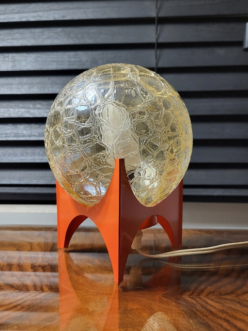 Table lamp with orange base and glass globe shade