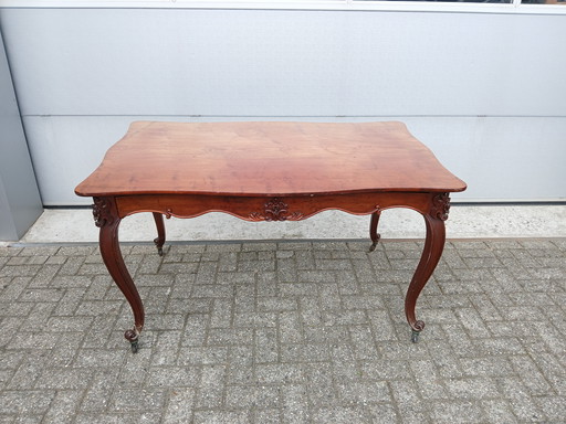 The antique dining table is made of mahogany and has a Louis XV style.