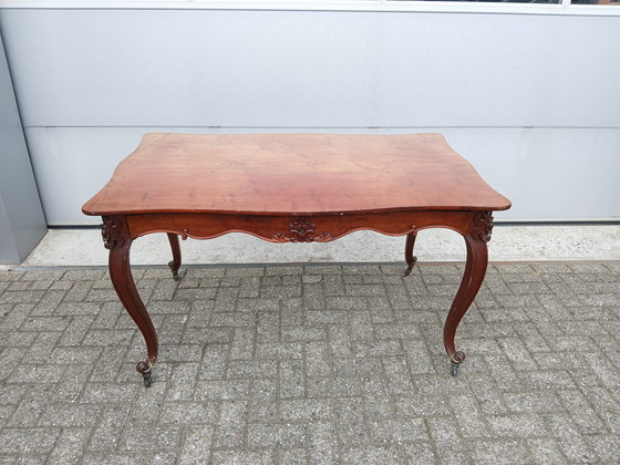 Image 1 of The antique dining table is made of mahogany and has a Louis XV style.