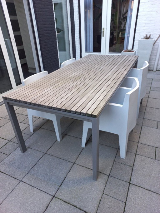 Mesa de comedor moderna para jardín con estructura de aluminio y madera de teca.
