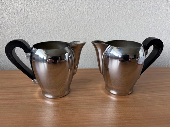 Image 1 of 2 vintage Carlo Alessi stainless steel milk jugs with rounded tops and Bakelite handles.