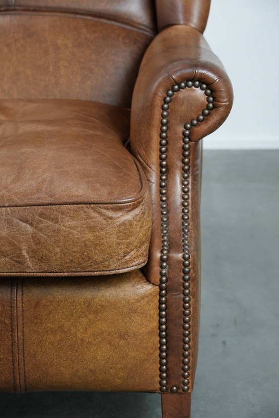 Image 1 of Tijdloze cognac kleurige oorfauteuil in Engelse stijl gemaakt van rundleer afgewerkt met siernagels