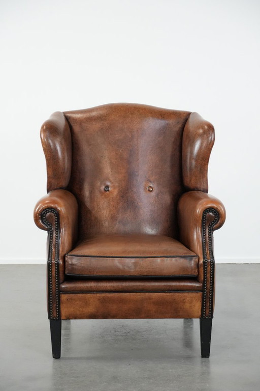 Comfortabele en tijdloze schapenleren oorfauteuil met siernagels en zwarte biezen