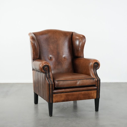 Comfortabele en tijdloze schapenleren oorfauteuil met siernagels en zwarte biezen