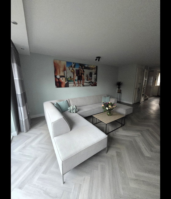 Image 1 of Modèle sur bloc de stock, comprenant un coin salon et un pouf séparé.