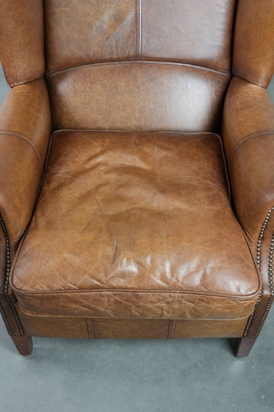 Image 1 of Tijdloze cognac kleurige oorfauteuil in Engelse stijl gemaakt van rundleer afgewerkt met siernagels