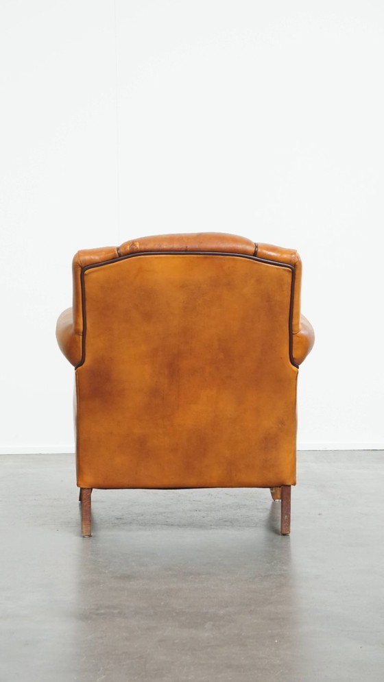 Image 1 of Schapenleren armchair met een afwerking met donkerbruine biezen