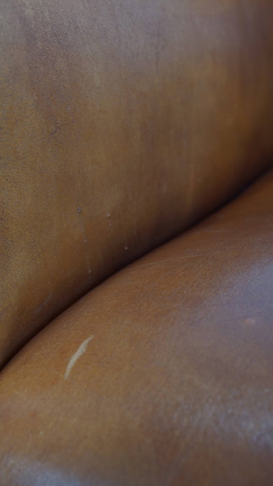 Image 1 of Schapenleren armchair met een afwerking met donkerbruine biezen