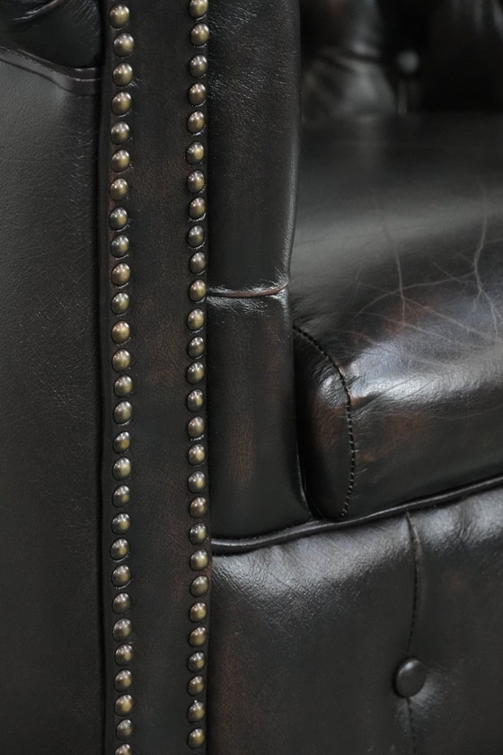 Image 1 of Donkere luxe rundleren Chesterfield clubfauteuil in Engelse stijl, afgewerkt met siernagels