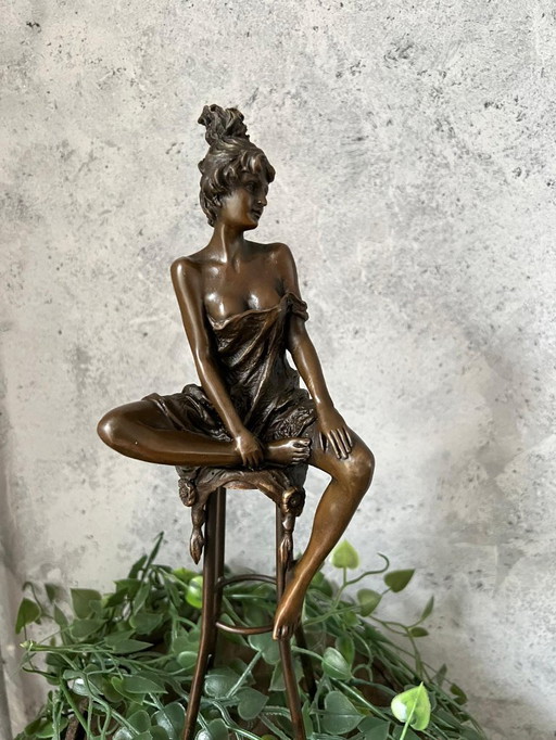 Bronzestatue einer Frau auf einem Hocker