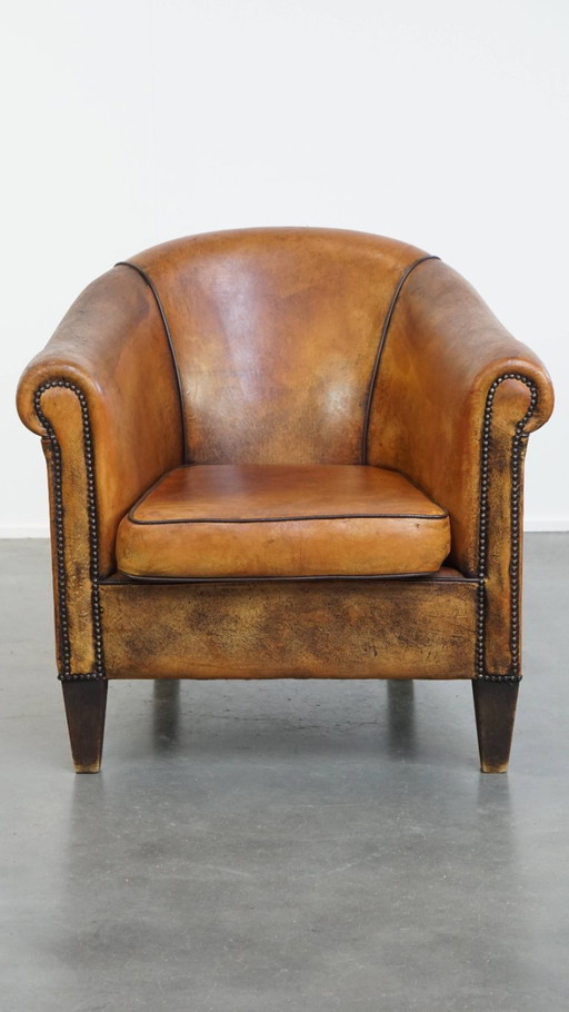 Fauteuil club vintage en cuir de mouton avec rivets décoratifs et passepoils noirs