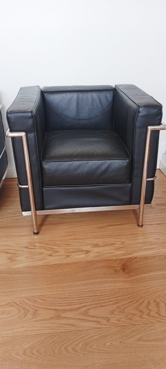 Image 1 of Een set van twee zwarte leren fauteuils en een bank.