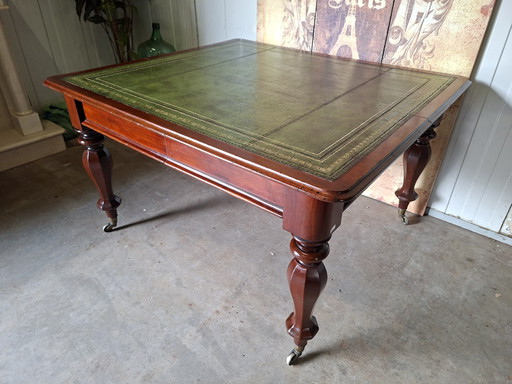 Scrivania antica, con piano in pelle intarsiata, con 2 cassetti. Dimensioni: 130x115 cm e altezza 74 cm.