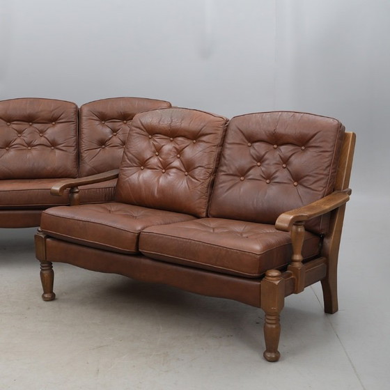 Image 1 of A vintage brown three-piece sofa set in leather with wooden armrests and turned legs, comprising a 1-seater, 2-seater and 3-seat
