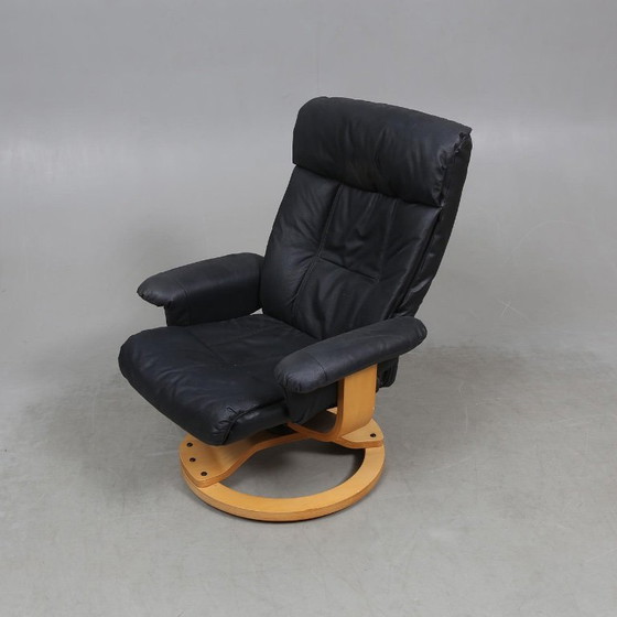 Image 1 of Sweden-origin Scandinavian lounge armchair with a matching ottoman, featuring a black leather and wood frame, in good condition 