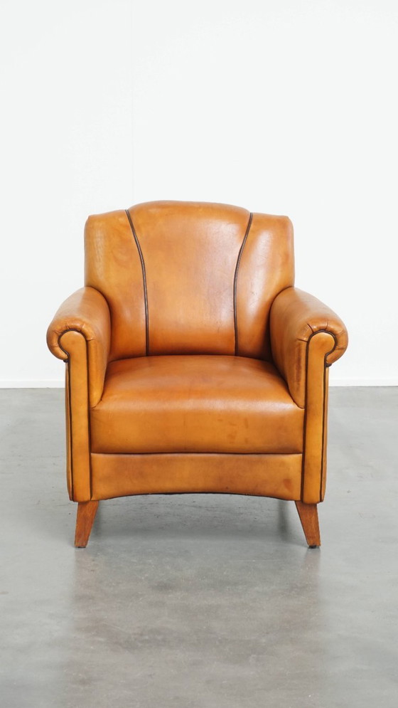 Image 1 of Schapenleren armchair met een afwerking met donkerbruine biezen