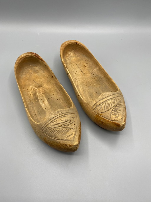 Paire de sabots anciens en bois sculpté avec motif de feuilles