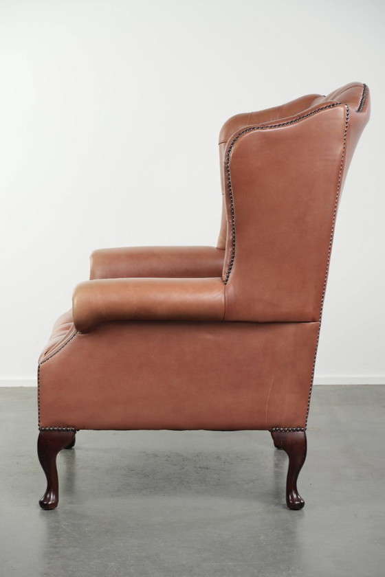 Image 1 of Fauteuil Chesterfield à oreilles en cuir de vachette anglais, assise capitonnée, avec une belle patine et de jolies couleurs.