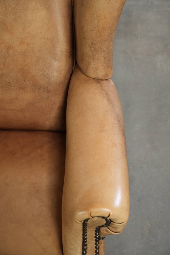 Image 1 of Dos hermosos sillones orejeros de piel de vaca clara con un estilo inglés atemporal y gran comodidad.