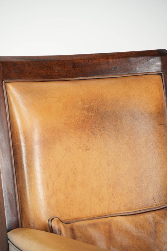 Image 1 of Cómodo sillón de diseño Art Déco en color coñac, fabricado en piel de oveja combinada con madera y con respaldo alto.