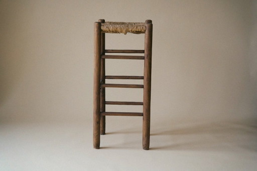 Taburete alto de madera con asiento de junco.