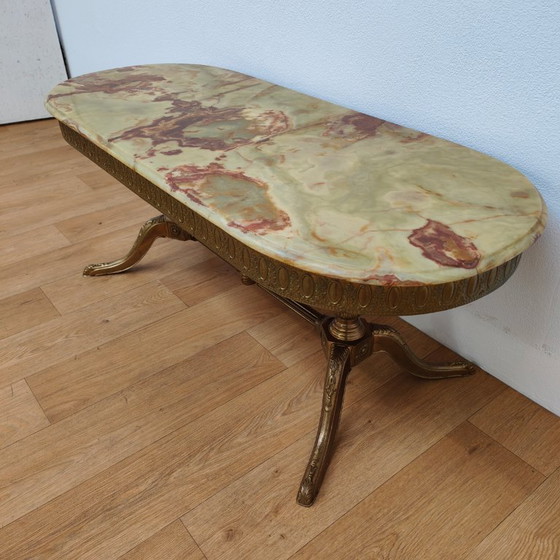 Image 1 of Table basse ovale de style Hollywood Regency avec plateau en marbre et piètement en laiton.