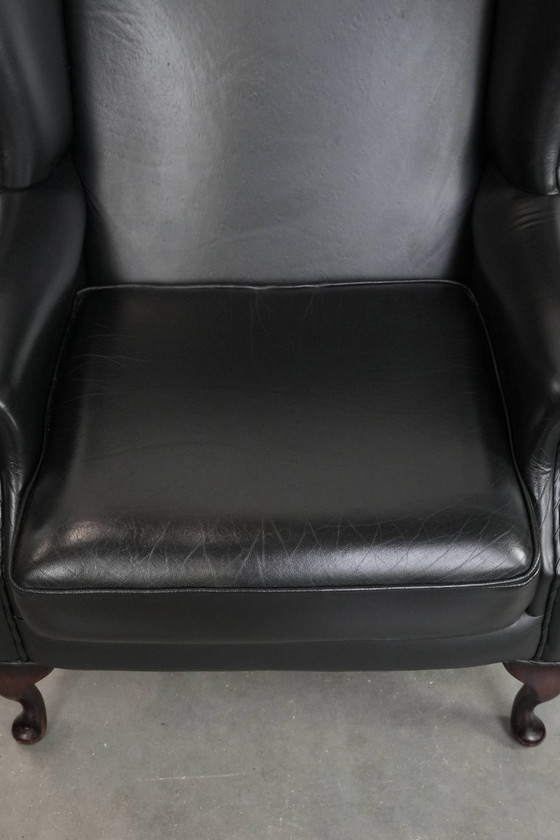 Image 1 of Smooth black cowhide Chesterfield wingback armchair in English style with color-matched piping