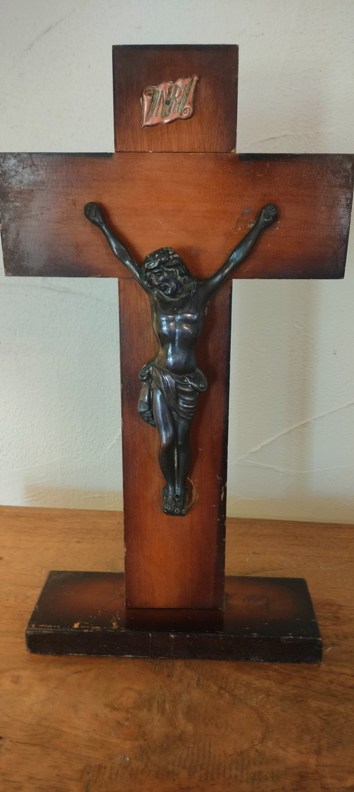 Small copper crucifix on a wooden plank