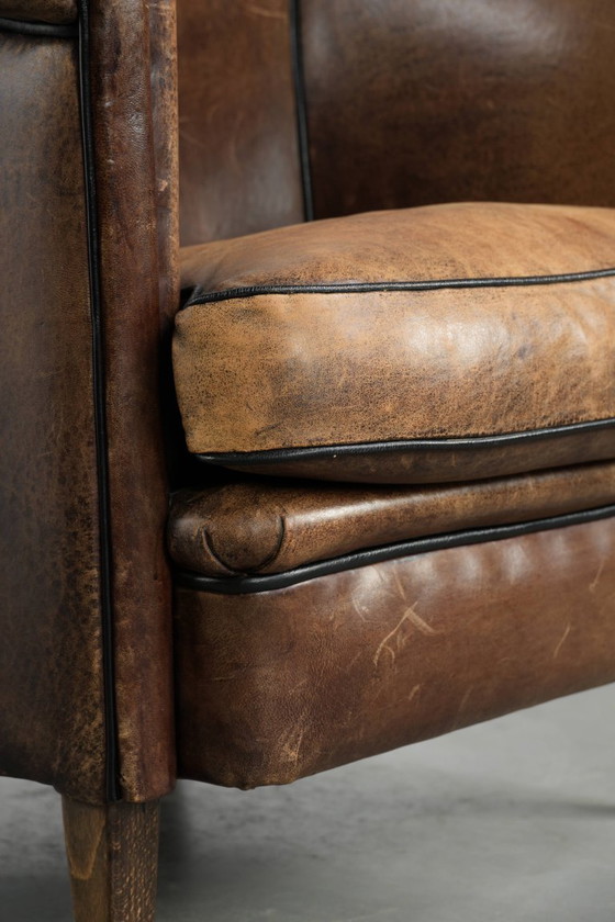 Image 1 of Leuke vintage schapenleren clubfauteuil in Engelse stijl met zwarte biezen