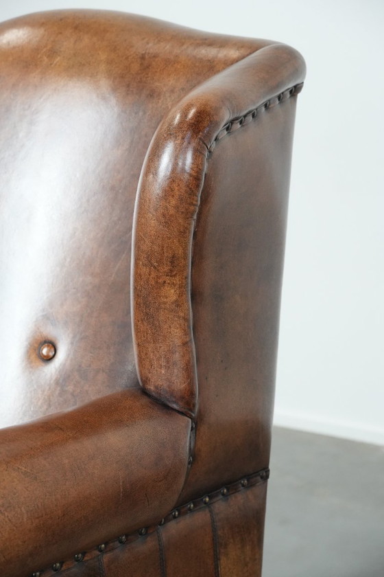 Image 1 of Comfortabele en tijdloze schapenleren oorfauteuil met siernagels en zwarte biezen