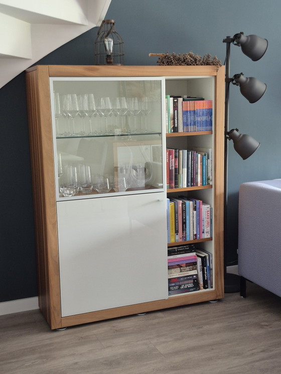 Image 1 of Table haute Hülsta Xelo Design – Bois de noyer, verre blanc brillant et vitrine
