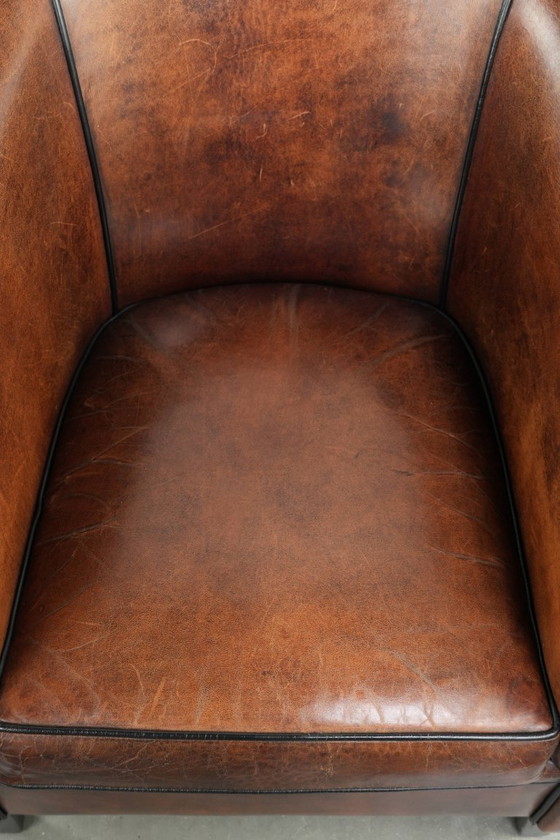 Image 1 of Mooie en karaktervolle schapenleren clubfauteuil met mooie diepe warme kleuren, zwarte biezen en een comfortabele zit