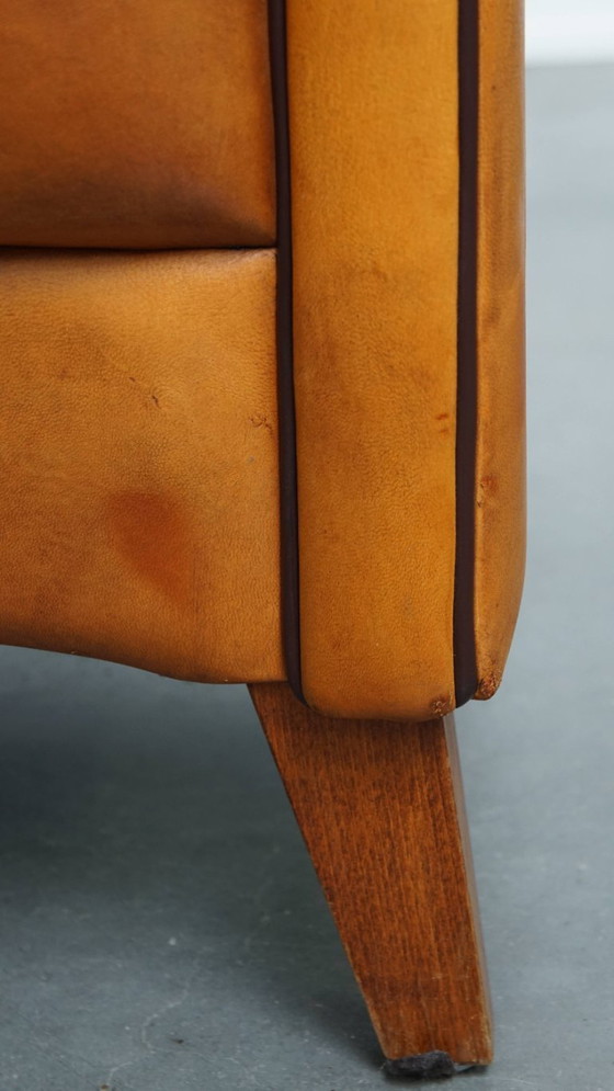 Image 1 of Schapenleren armchair met een afwerking met donkerbruine biezen