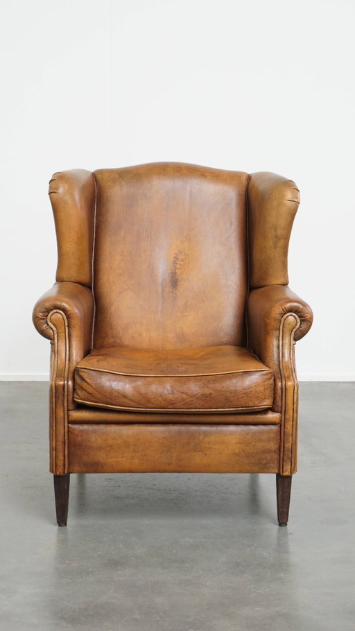Karaktervolle vintage schapenleren oorfauteuil met een mooi patina