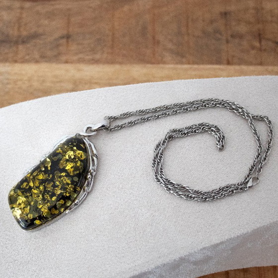Image 1 of Grande ciondolo in ambra baltica verde: incastonato in metallo color argento con decorazioni floreali.