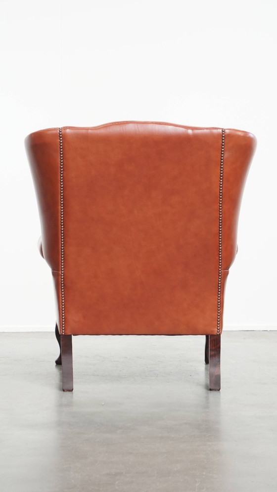 Image 1 of Elegante en comfortabele gladde Engelse rundleren chesterfield oorfauteuil met sierlijke pootjes